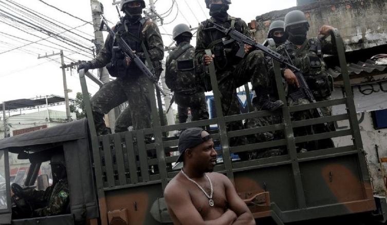 En el frente. Una patrulla armada para la guerra recorre las calles de una de las favelas de Río, donde los narcos ponen vallados y montan milicias con jóvenes igualmente armados. (Reuter)