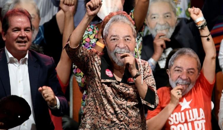 Dilma Roussef con una máscara de Lula da Silva, durante el acto del Partido de los Trabajadores. / AFP PHOTO / DOUGLAS MAGNO