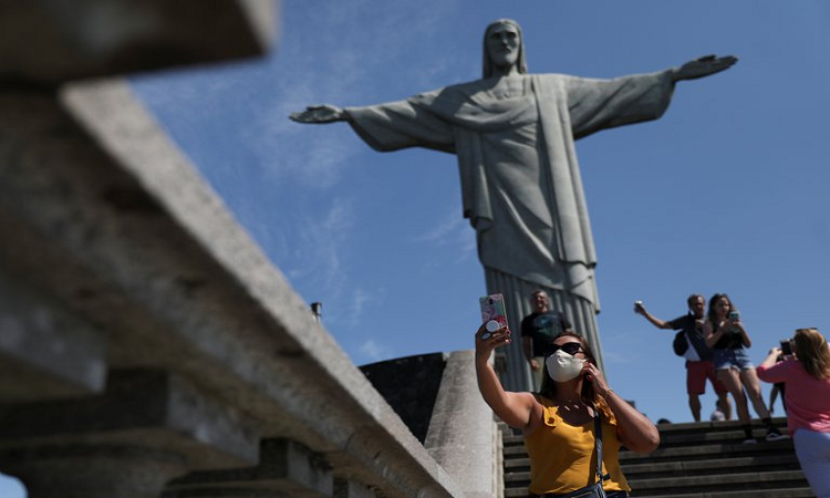 Turistas se sacan selfies con el Cristo Redentor durante la reapertura del ícono carioca (REUTERS)