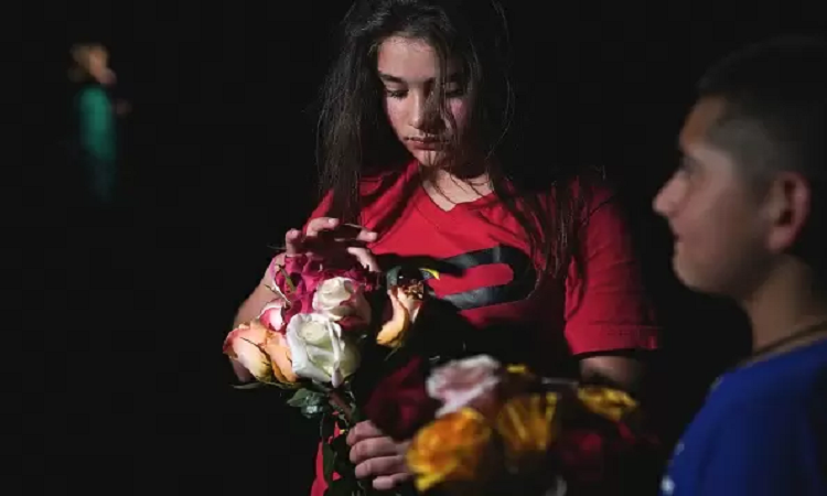 Una niña pone flores en un altar frente a la escuela Robb Elementary, en Uvalde, Texas, en donde el 24 de mayo un joven de 18 años, Salvador Ramos, mató a 19 niños y a 2 maestros. Antes había disparado a su abuela. Foto: GETTY IMAGES