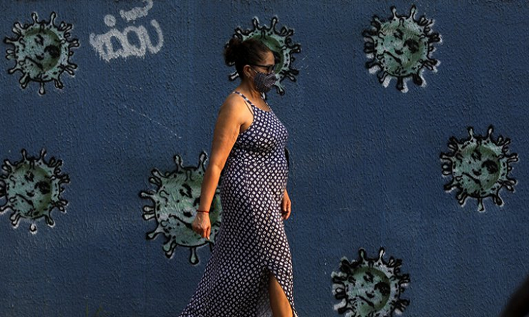 A woman walks next to graffiti depicting viruses with the face of Brazil ´s President Jair Bolsonaro, amid the coronavirus disease (COVID-19) outbreak, in Rio de Janeiro, Brazil, October 7, 2020. REUTERS/Ricardo Moraes