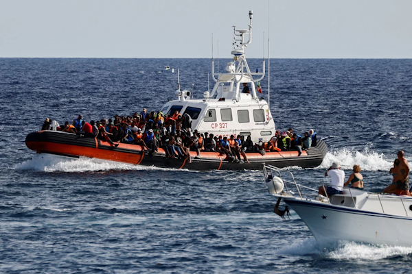  Un barco de la Guardia Costera italiana que transportaba inmigrantes rescatados en el mar pasa cerca de un barco turístico, en la isla de Lampedusa, Italia. 18 de septiembre de 2023. REUTERS/Yara Nardi